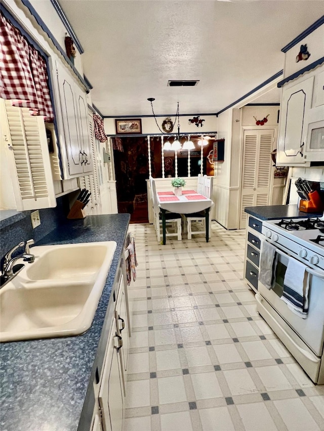 kitchen featuring sink, white cabinets, a textured ceiling, and white gas range oven