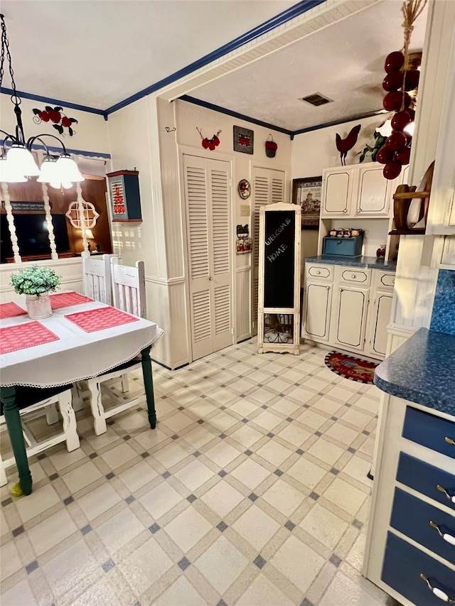 kitchen featuring pendant lighting, cream cabinets, and crown molding