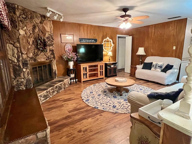 living room featuring ceiling fan, hardwood / wood-style flooring, a fireplace, and rail lighting