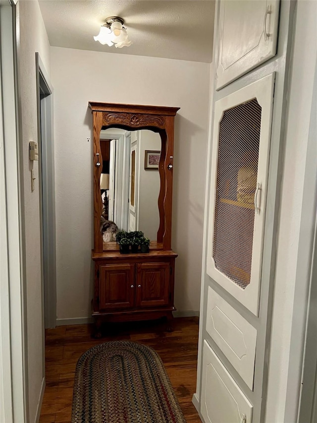 corridor featuring a textured ceiling and dark hardwood / wood-style flooring