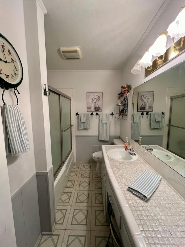 full bathroom with toilet, vanity, bath / shower combo with glass door, and ornamental molding