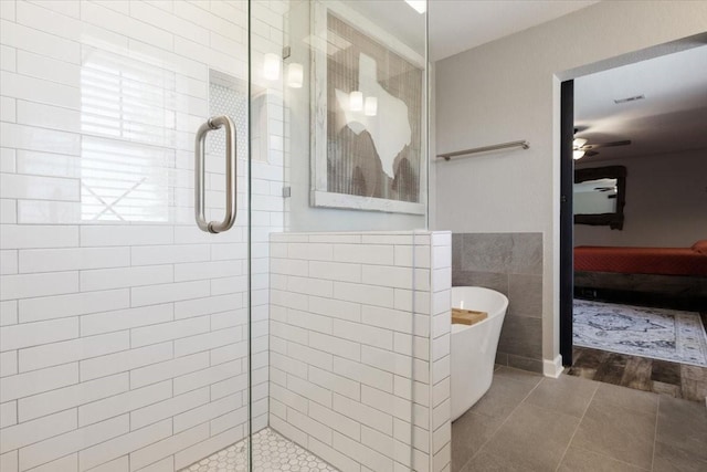 bathroom with plus walk in shower, ceiling fan, tile patterned flooring, and tile walls