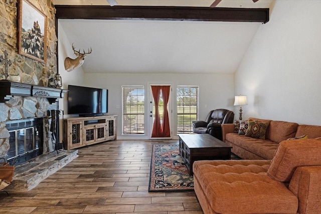 living room with ceiling fan, high vaulted ceiling, beam ceiling, and a stone fireplace