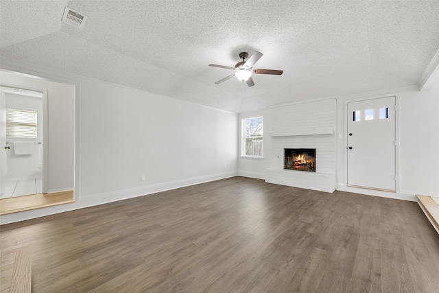 unfurnished living room with ceiling fan, a textured ceiling, dark hardwood / wood-style floors, and a fireplace