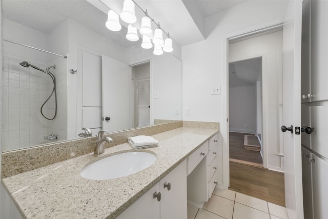 bathroom featuring vanity, tile patterned floors, a textured ceiling, and a tile shower