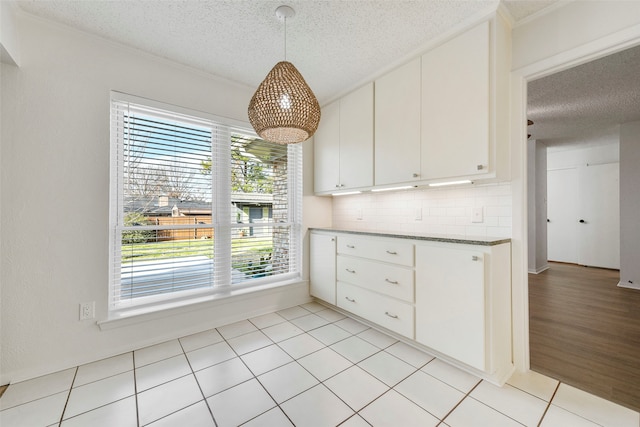 kitchen featuring decorative backsplash, a healthy amount of sunlight, white cabinets, and decorative light fixtures