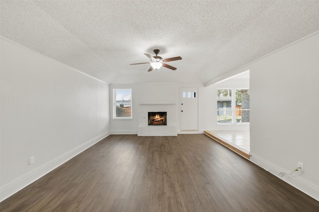 unfurnished living room featuring ceiling fan, a fireplace, dark hardwood / wood-style flooring, and a textured ceiling