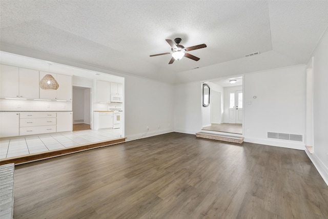 unfurnished living room featuring a raised ceiling, ceiling fan, a textured ceiling, and light hardwood / wood-style flooring