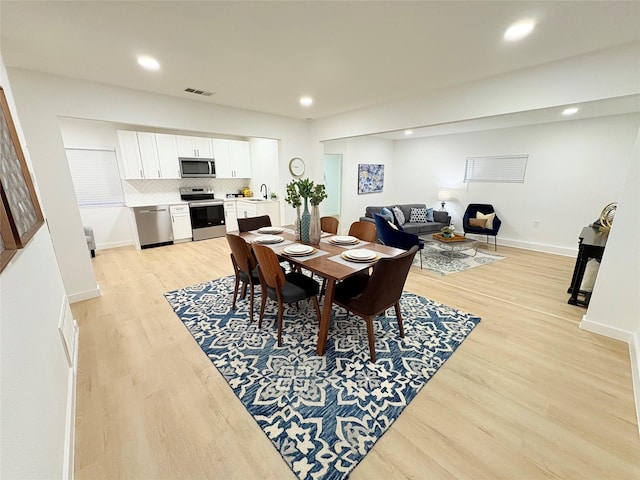 dining room featuring baseboards, light wood finished floors, visible vents, and recessed lighting