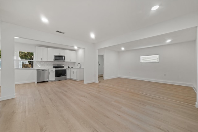 unfurnished living room featuring light hardwood / wood-style flooring and sink