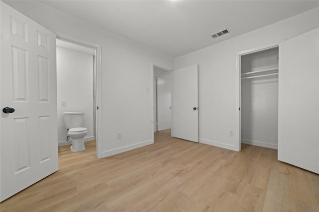 unfurnished bedroom with a closet, connected bathroom, and light hardwood / wood-style floors