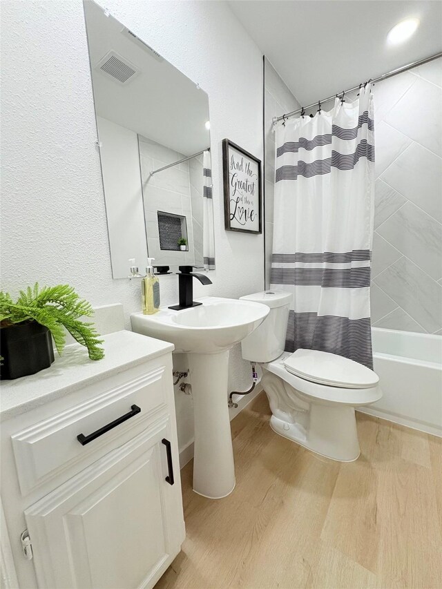 bathroom with toilet, hardwood / wood-style flooring, a tile shower, and vanity