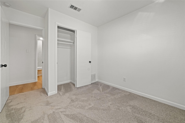 unfurnished bedroom featuring light colored carpet and a closet