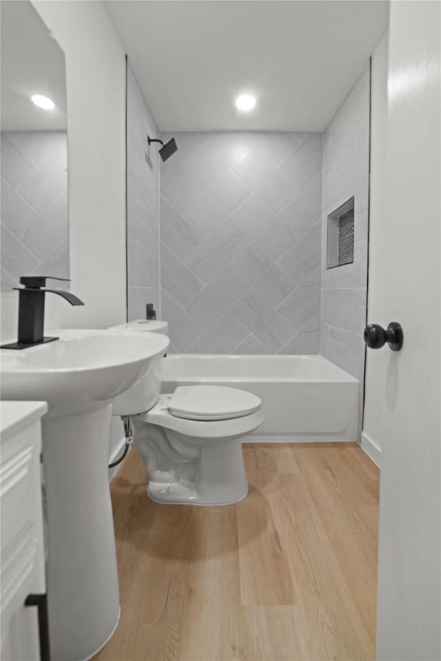 bathroom featuring toilet, tiled shower / bath combo, and hardwood / wood-style flooring