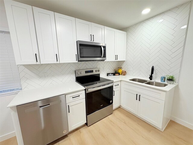 kitchen featuring appliances with stainless steel finishes, white cabinetry, light wood-type flooring, and decorative backsplash