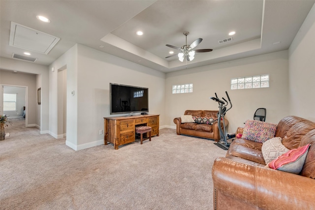 carpeted living room featuring a raised ceiling, ceiling fan, and a healthy amount of sunlight