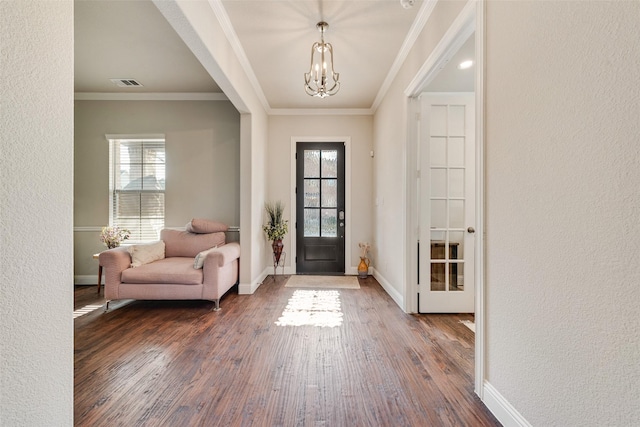 entryway with dark wood-type flooring, an inviting chandelier, and crown molding