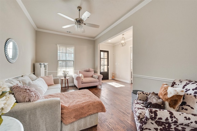 living room with ceiling fan with notable chandelier, wood-type flooring, and crown molding