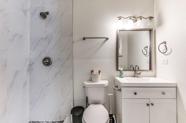 bathroom featuring a tile shower, vanity, and toilet