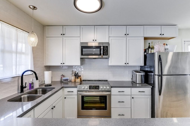 kitchen featuring stainless steel appliances, decorative light fixtures, white cabinetry, and sink