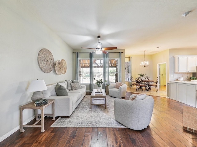 living room with ceiling fan with notable chandelier and hardwood / wood-style flooring