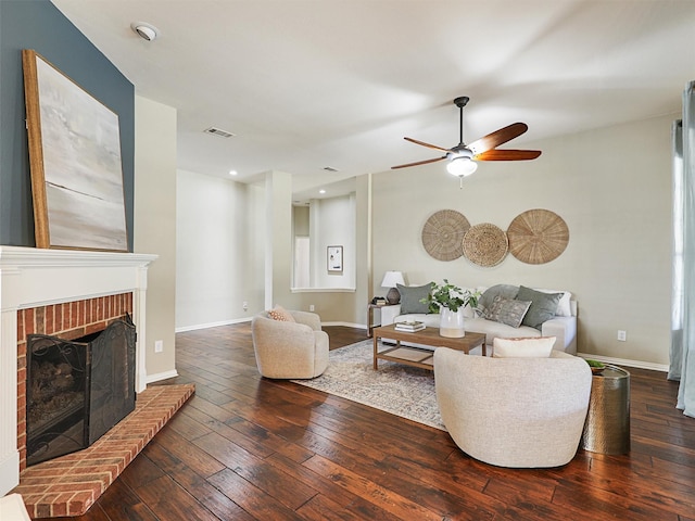 living room featuring a fireplace, ceiling fan, and dark wood-type flooring