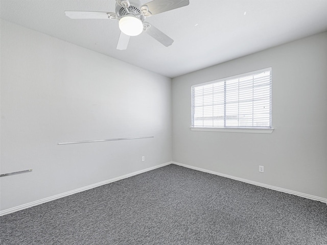 unfurnished room with ceiling fan and dark colored carpet