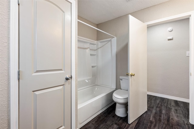 bathroom featuring a textured ceiling, bathing tub / shower combination, hardwood / wood-style floors, and toilet