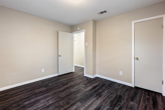 unfurnished bedroom featuring a textured ceiling and dark wood-type flooring