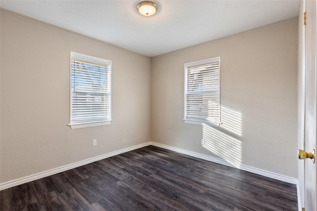 spare room with dark hardwood / wood-style flooring and a wealth of natural light