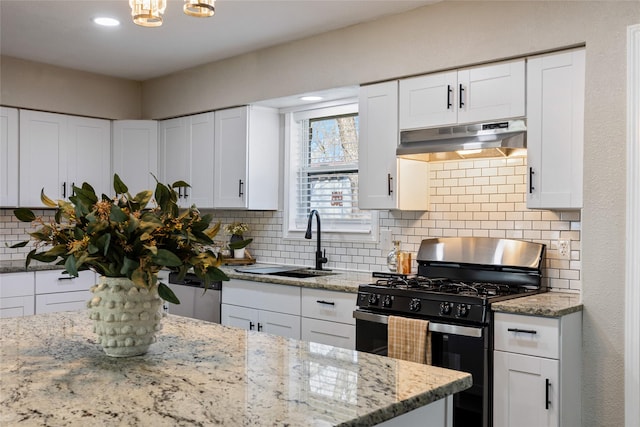 kitchen with sink, white cabinets, light stone counters, backsplash, and gas stove