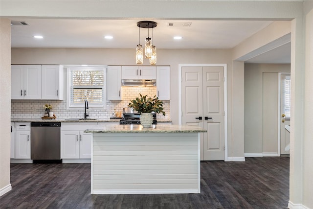 kitchen with hanging light fixtures, a center island, light stone counters, white cabinetry, and stainless steel dishwasher