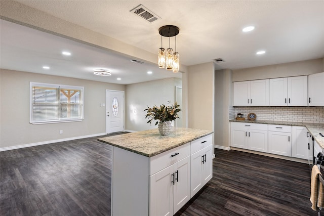 kitchen with white cabinetry, light stone countertops, decorative backsplash, dark hardwood / wood-style floors, and pendant lighting