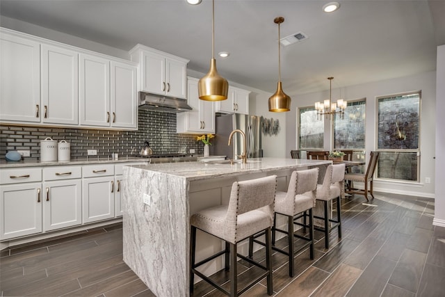 kitchen featuring a center island with sink, white cabinetry, and pendant lighting