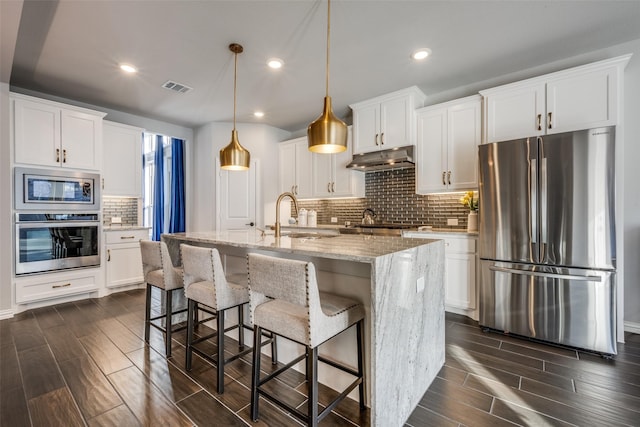 kitchen with sink, white cabinets, decorative light fixtures, a kitchen island with sink, and appliances with stainless steel finishes