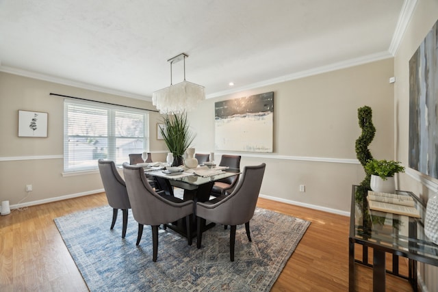 dining space with a chandelier, ornamental molding, and hardwood / wood-style flooring