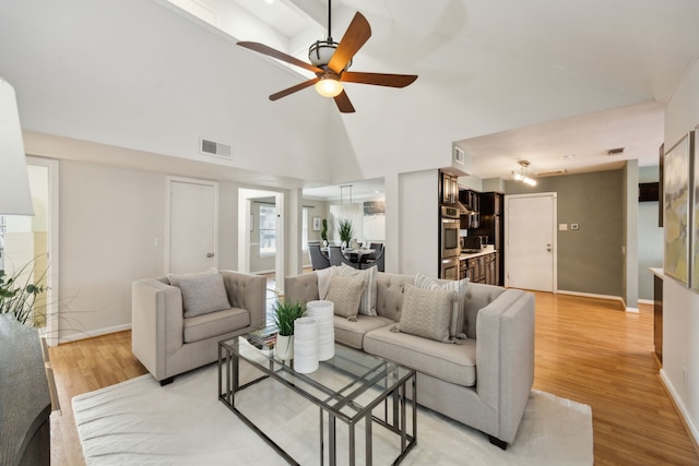 living room with high vaulted ceiling, ceiling fan, and light hardwood / wood-style floors