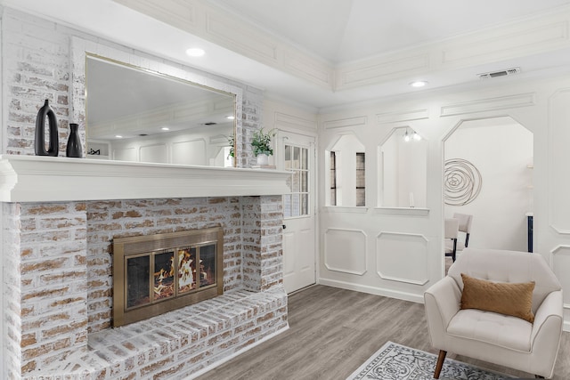 living room with a fireplace, ornamental molding, and wood-type flooring