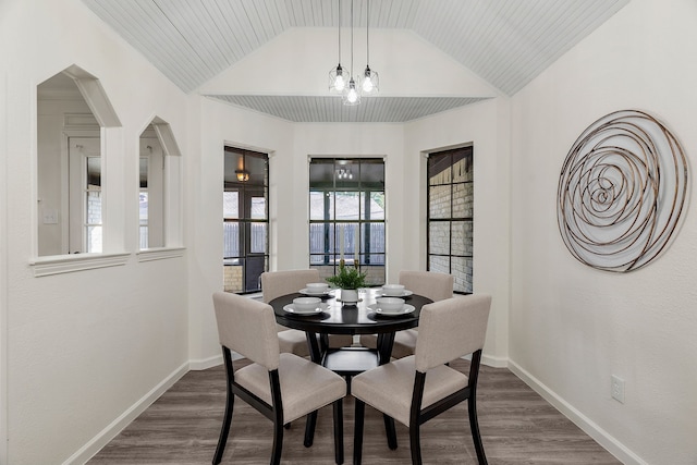 dining space with lofted ceiling, dark hardwood / wood-style flooring, and an inviting chandelier