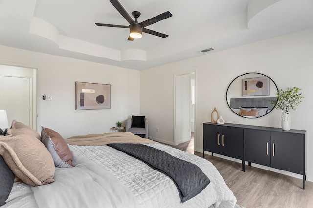 bedroom featuring hardwood / wood-style flooring, a raised ceiling, and ceiling fan