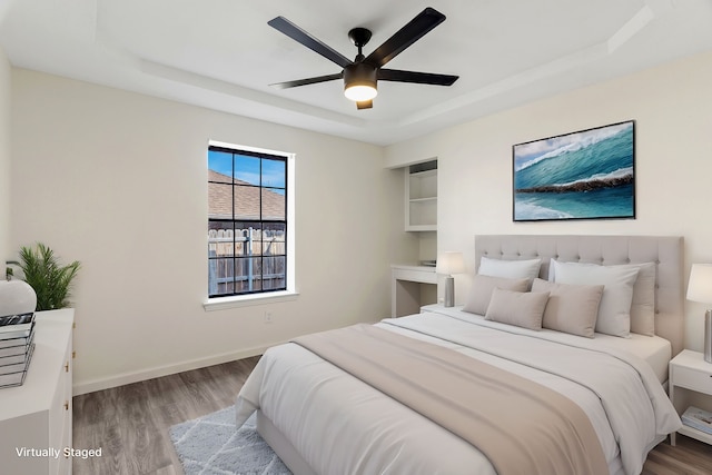 bedroom featuring ceiling fan, a tray ceiling, and light hardwood / wood-style floors