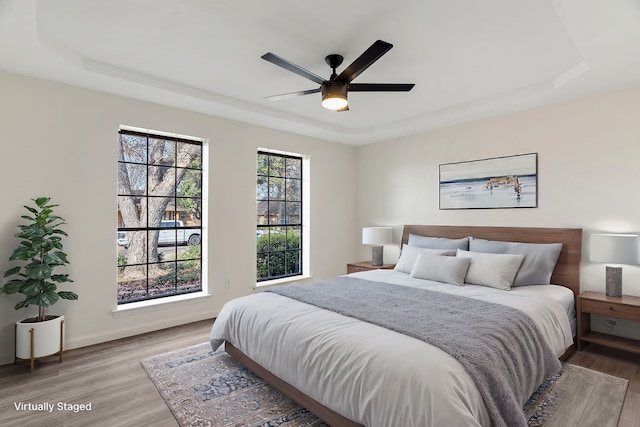 bedroom featuring a raised ceiling, ceiling fan, and hardwood / wood-style flooring