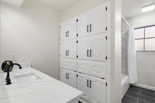 clothes washing area featuring dark tile patterned flooring and sink