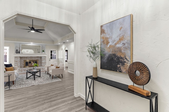 interior space with hardwood / wood-style floors, ornamental molding, ceiling fan, a fireplace, and lofted ceiling