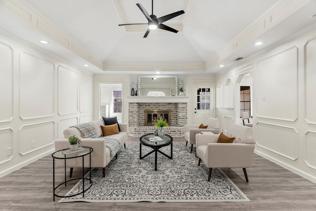 living room with vaulted ceiling, a brick fireplace, ornamental molding, and hardwood / wood-style flooring