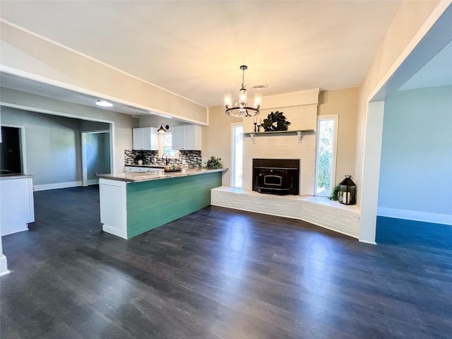 kitchen with white cabinetry, kitchen peninsula, backsplash, a chandelier, and pendant lighting