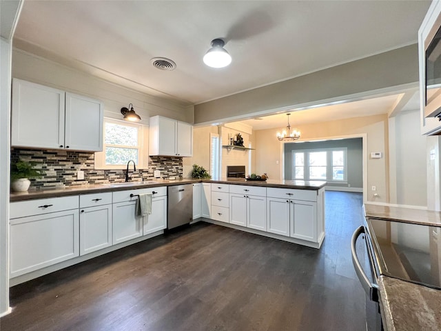 kitchen featuring pendant lighting, kitchen peninsula, sink, appliances with stainless steel finishes, and white cabinets