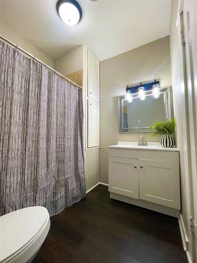 bathroom with toilet, vanity, wood-type flooring, a textured ceiling, and curtained shower