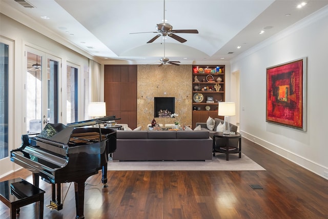 living room with lofted ceiling, ceiling fan, ornamental molding, built in shelves, and dark wood-type flooring