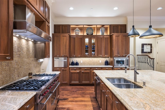 kitchen with stainless steel appliances, decorative backsplash, wall chimney range hood, and sink